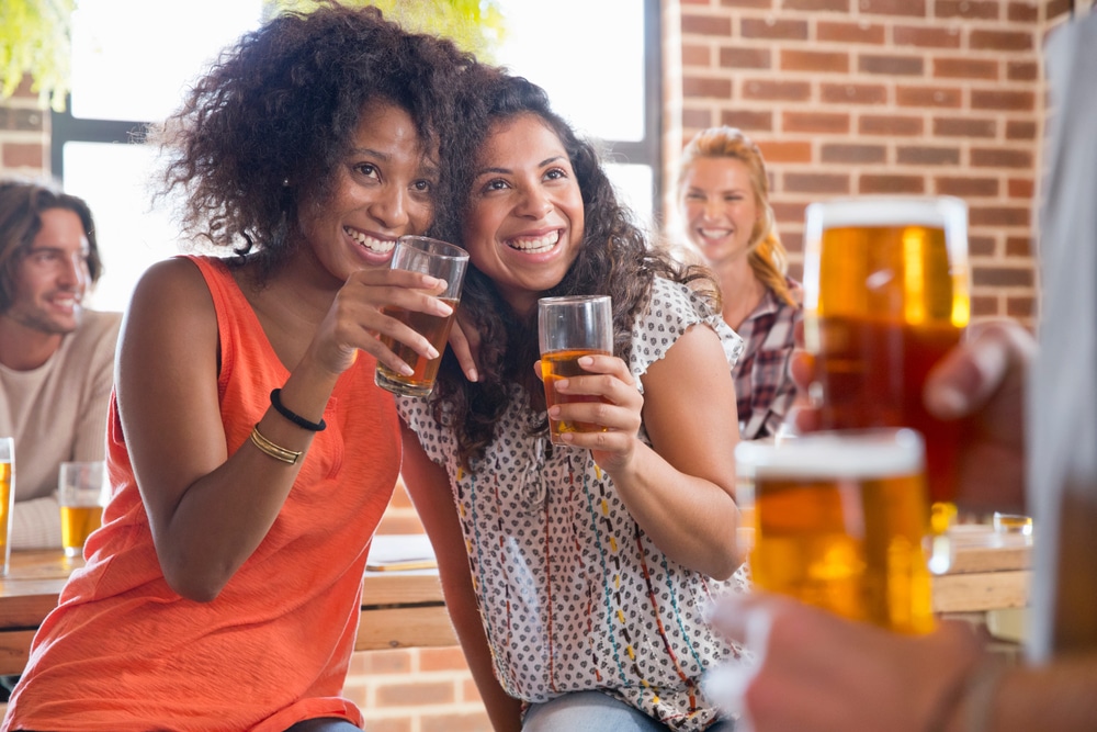 Two black women enjoying a beer at Okoboji Brewing Company, after wine tasting at Round Lake Vineyards near our Okoboji Hotel